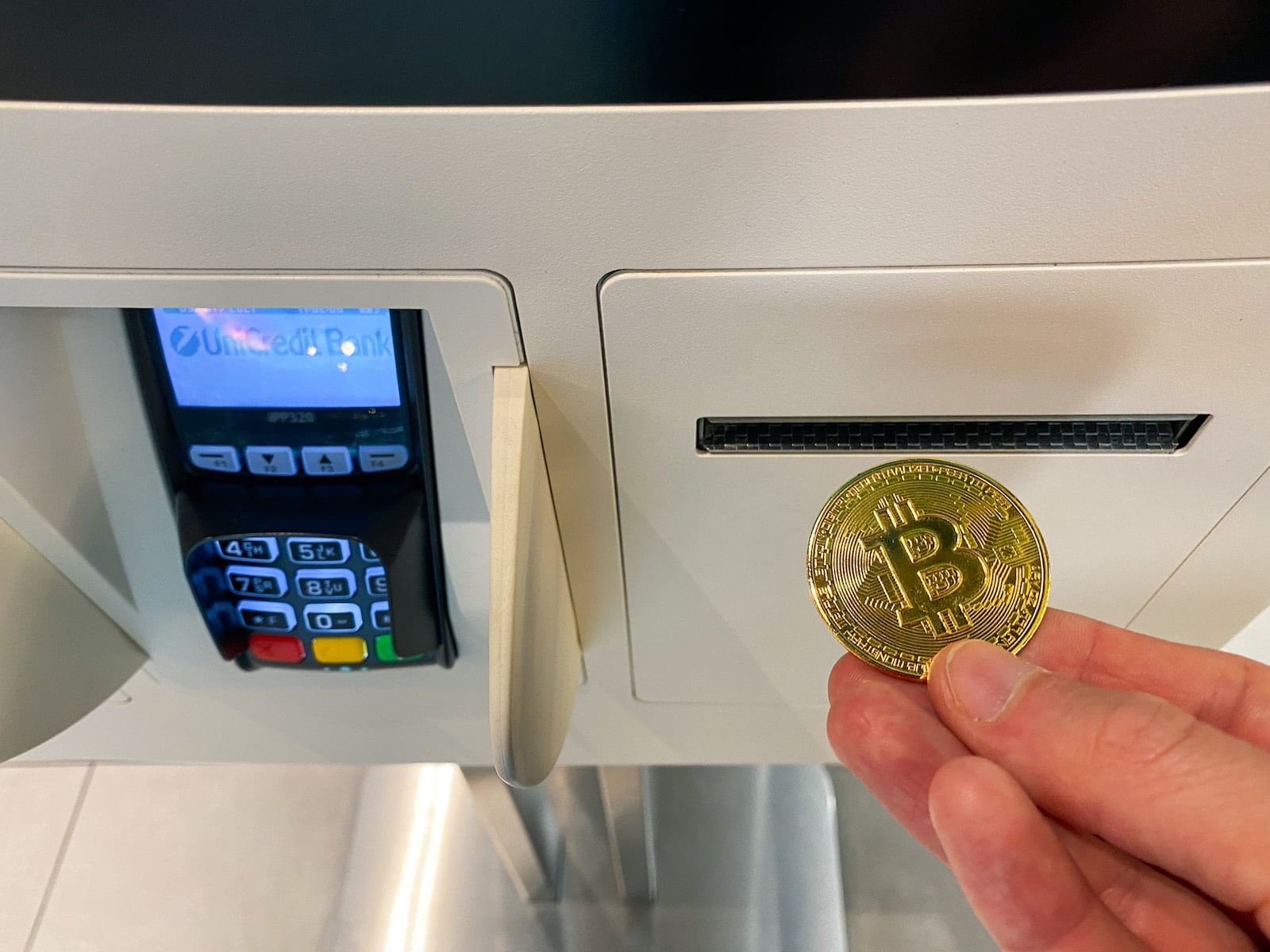 a hand holding a coin in front of a machine