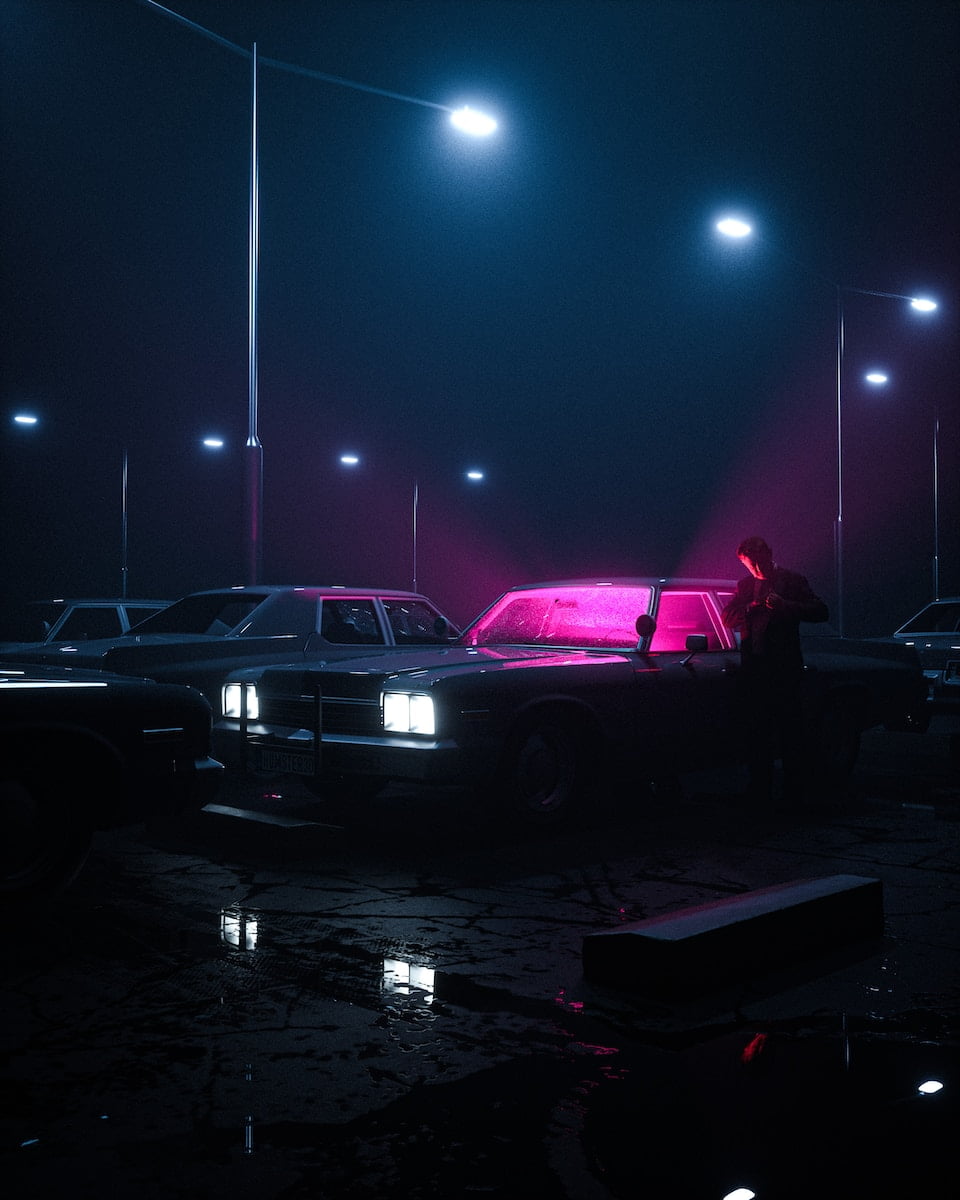 a group of cars parked in a parking lot at night